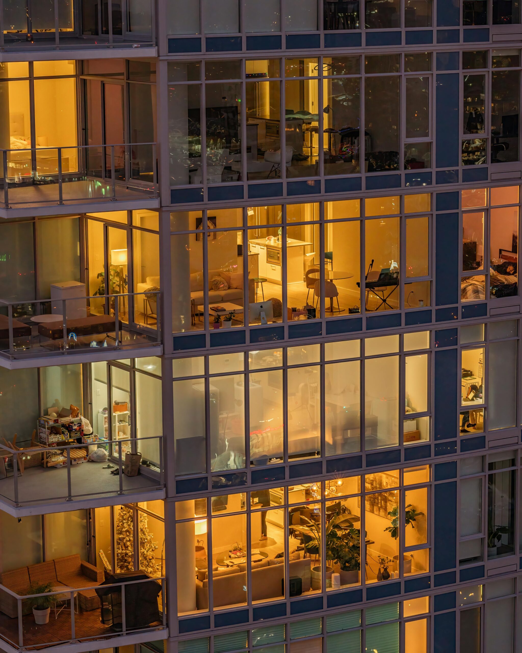 Warmly lit modern apartments in a Vancouver high-rise building at dusk.